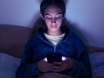 teenage girl using smartphone in dark